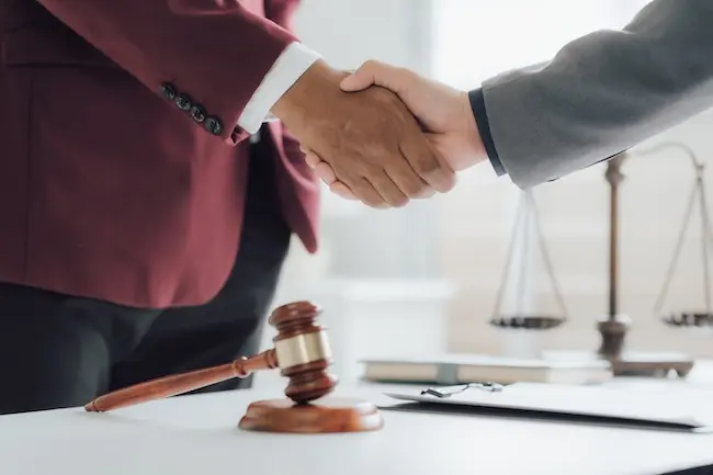 Truck accident lawyer and client shaking hands after reaching a settlement agreement for commercial truck collisions injury case.