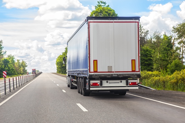 A large commercial semi-truck traveling on a highway, demonstrating the hidden dangers and safety risks of sharing the road with big rigs.