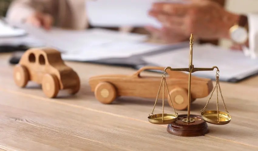 Wooden toy cars with scales of justice represent legal proceedings and liability claims arising from car accidents in North Carolina at LawyerPower® - The Law Office of Mark Farbman.